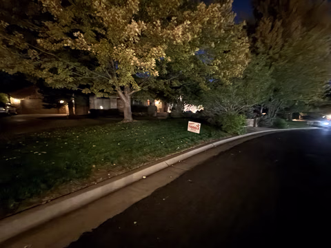 A Doug Tisdale sign beside a curving residential road at night.